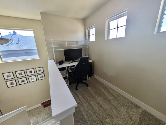 Versatile loft space featuring carpeting, light-toned walls, multiple windows providing natural illumination, and white trim