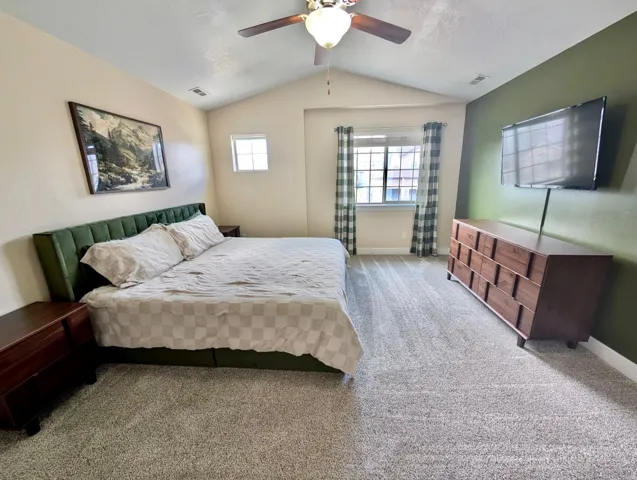 Vaulted ceiling bedroom featuring ample natural light, a ceiling fan, and carpet flooring