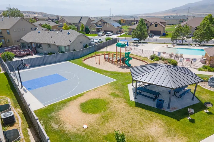 Community recreation area featuring a half-court basketball court, playground, covered picnic pavilion, and fenced swimming pool