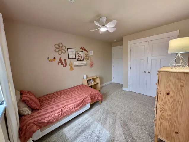 Carpeted room featuring a ceiling fan with integrated lighting, a double-door closet with white paneled doors, and a single window with white trim