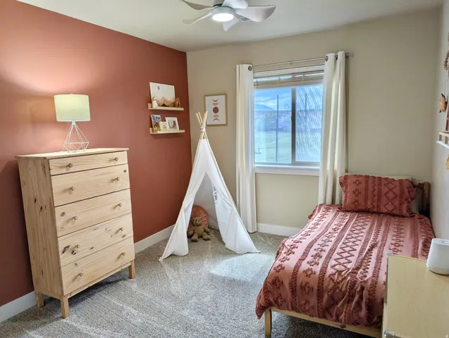 Room featuring plush carpeting, a single window, a ceiling fan, and a painted accent wall