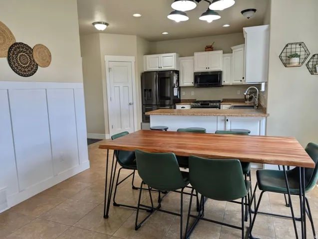 Kitchen and dining area featuring a wood-finish dining table, recessed lighting, tile flooring, and white board and batten paneling