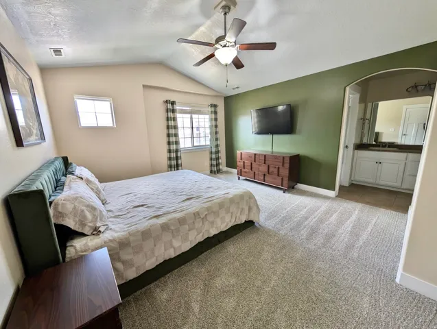 Carpeted room with vaulted ceiling and ceiling fan