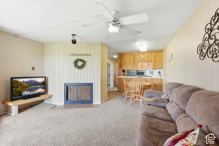 Open-concept living space with carpet flooring and a ceiling fan
