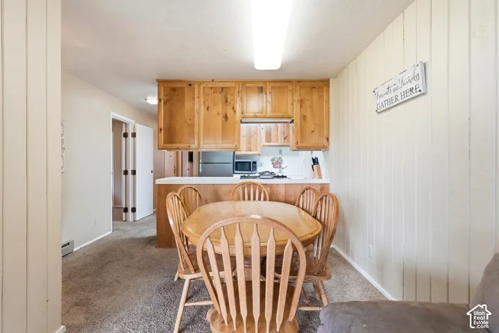 Compact kitchen and dining area featuring wood cabinetry, white countertops, and a white tile backsplash