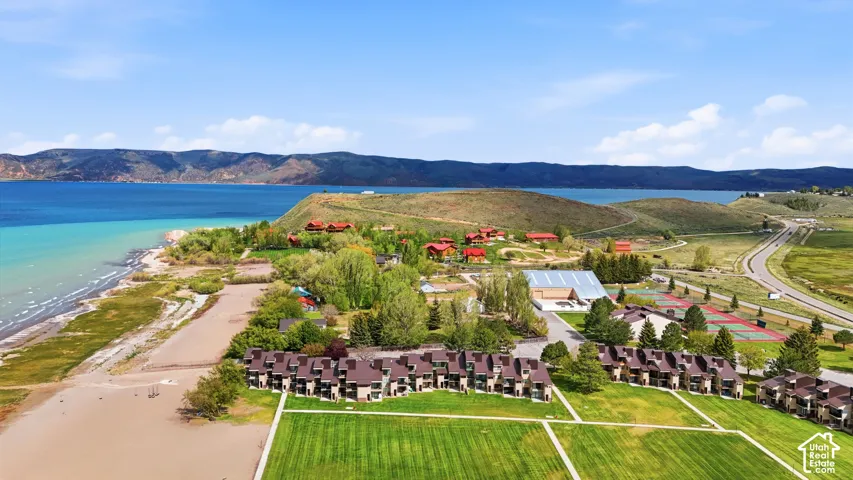 Expansive waterside property featuring multiple residential structures, large grassy areas, and visible tennis courts