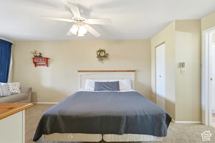 Carpeted bedroom with a ceiling fan, a built-in closet with bifold doors, and an open doorway
