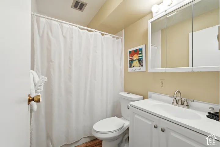 Bathroom featuring a white vanity with integrated sink, brushed nickel faucet, wall-mounted mirrored medicine cabinet, and a toilet
