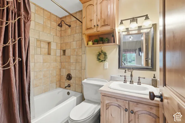 Bathroom featuring a tiled shower with integrated niches, a white bathtub, and a vanity with a white basin and wood-finish cabinetry