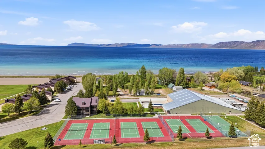Expansive recreational area featuring multiple tennis courts, a large sports facility, and direct access to the waterfront