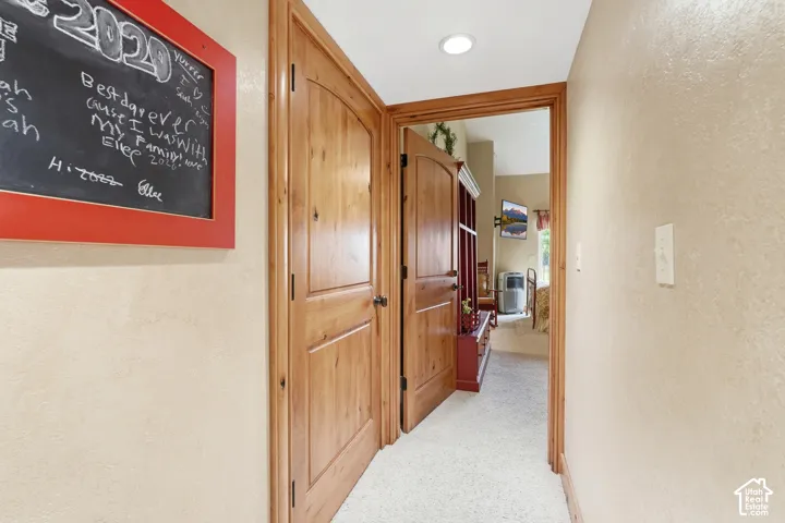 Hallway featuring light wood-finish doors and trim, neutral wall color, and recessed lighting