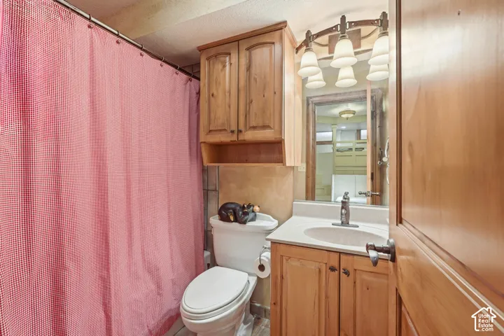 Bathroom featuring a single vanity with a white countertop, wood-finish cabinetry, and an overhead multi-bulb light fixture