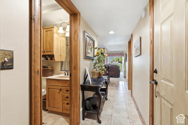 Hallway featuring neutral-toned tile flooring, recessed lighting, and natural wood trim throughout