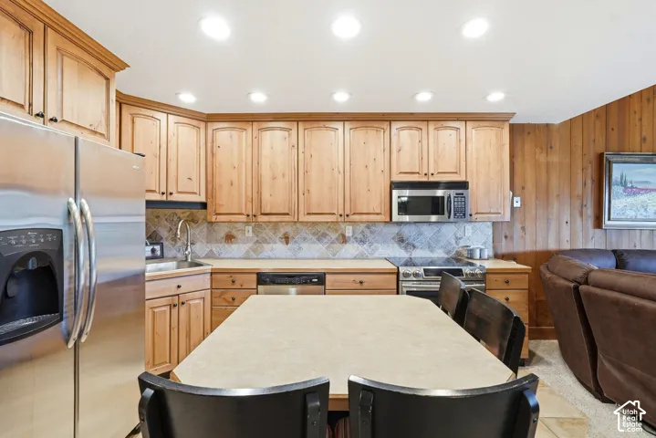 Kitchenette featuring wood cabinetry, stainless steel appliances, and a tiled backsplash