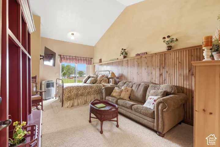 Vaulted ceiling room featuring carpet flooring, built-in vertical wood paneling, and a window with outdoor scenery