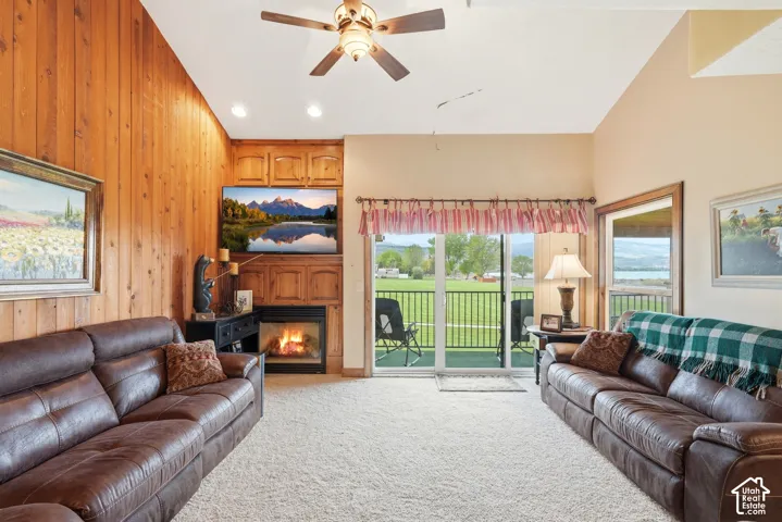 Living area featuring a vaulted ceiling with wood paneling, integrated fireplace, built-in cabinetry, recessed lighting, and sliding glass door access to an exterior deck