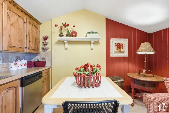Kitchen area featuring wood-finish cabinetry, a stainless steel dishwasher, and a tile backsplash