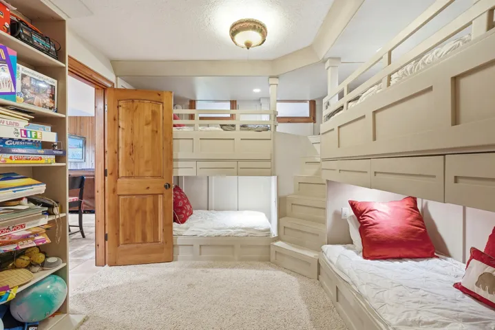 Room featuring built-in bunk beds with integrated storage, wood-finish door, sconce lighting, and carpet flooring