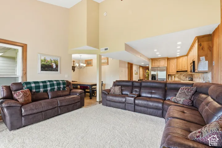 Spacious living area featuring vaulted ceilings, plush carpeting, and recessed lighting