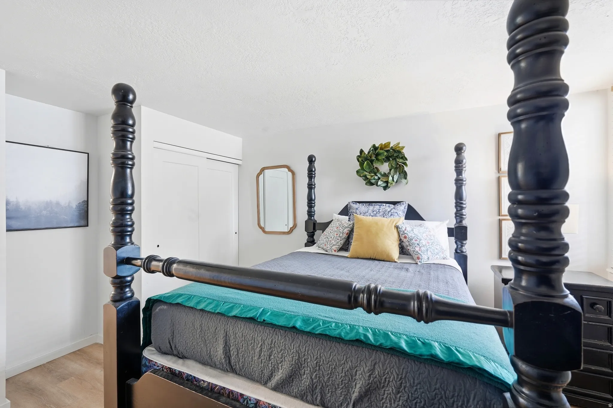 Bedroom featuring light wood-finish flooring, white walls, and a built-in sliding door closet