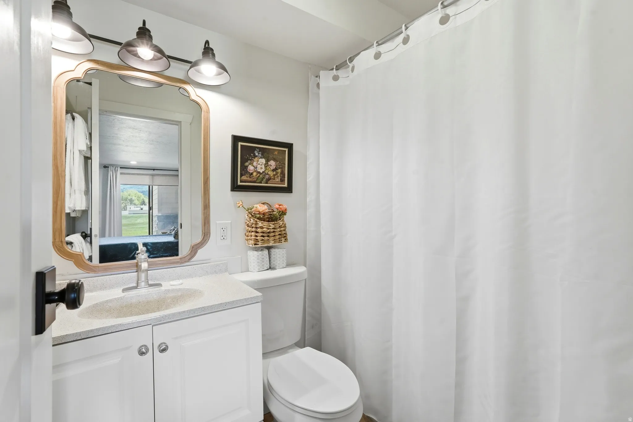 Bathroom featuring a white vanity with an integrated sink, a light-colored countertop, and a classic curved-frame mirror