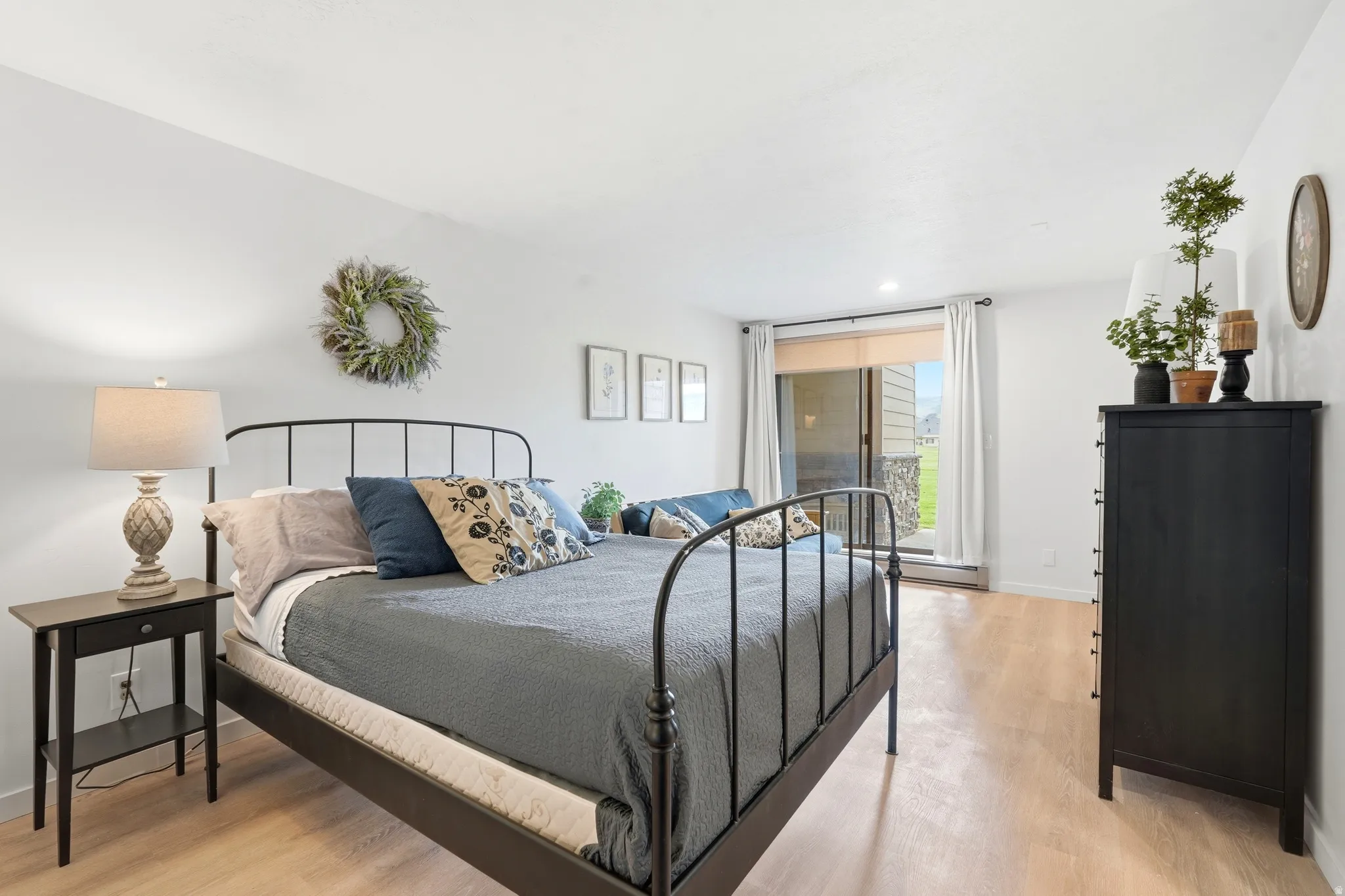 Spacious room featuring light wood-finish flooring, white walls, and a sliding glass door providing exterior access