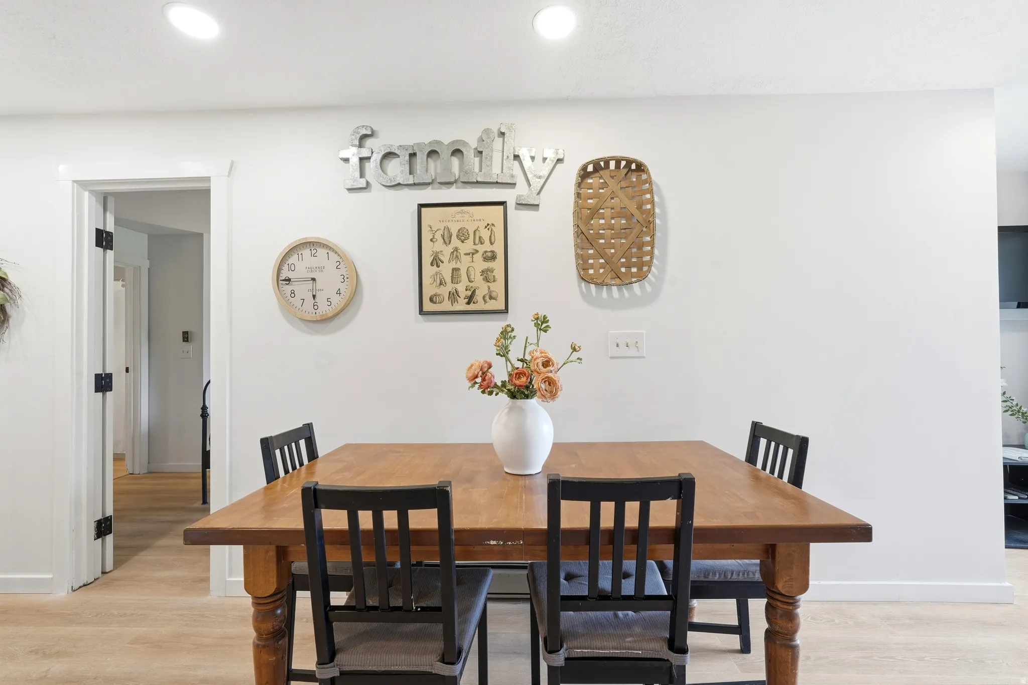 Dining area featuring light wood-finish flooring, recessed lighting, and a doorway with dark hardware