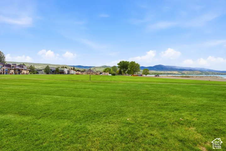 Expansive green space featuring a large grassy field with distant buildings and mountainous terrain