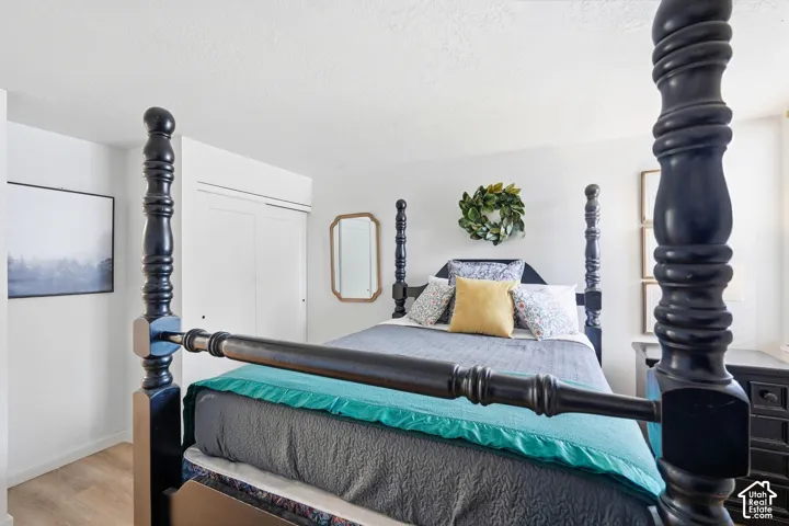 Bedroom featuring light wood-finish flooring, white walls, and a built-in sliding door closet