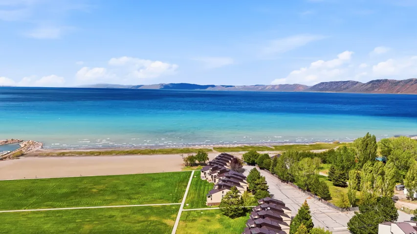 Expansive waterfront setting featuring a sandy beach, clear blue water, and distant mountains