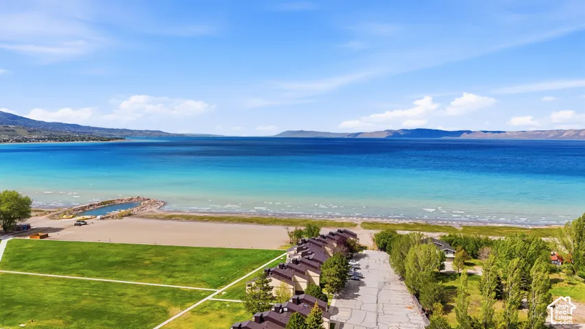 Expansive waterfront setting featuring a sandy beach area, a boat launch, and a large green space