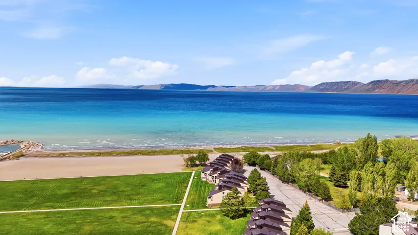 Expansive waterfront setting featuring a sandy beach, clear blue water, and distant mountains