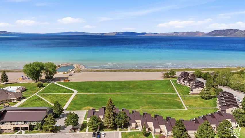 Expansive waterfront property featuring a large grassy area and sandy beach