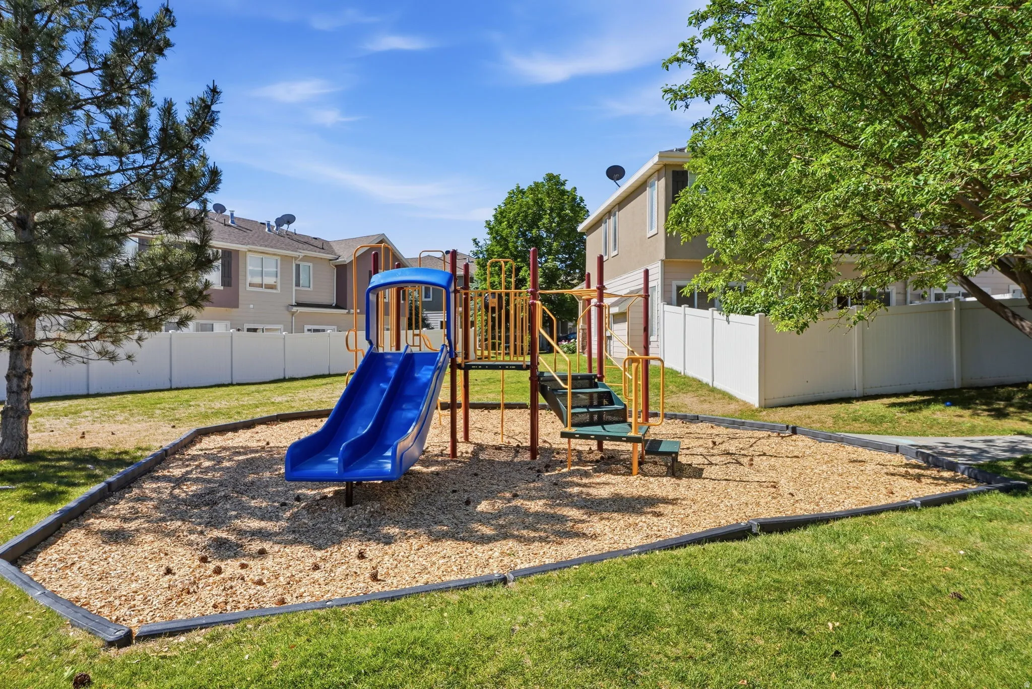 Community playground featuring  slides, play structure, and wood chip surfacing