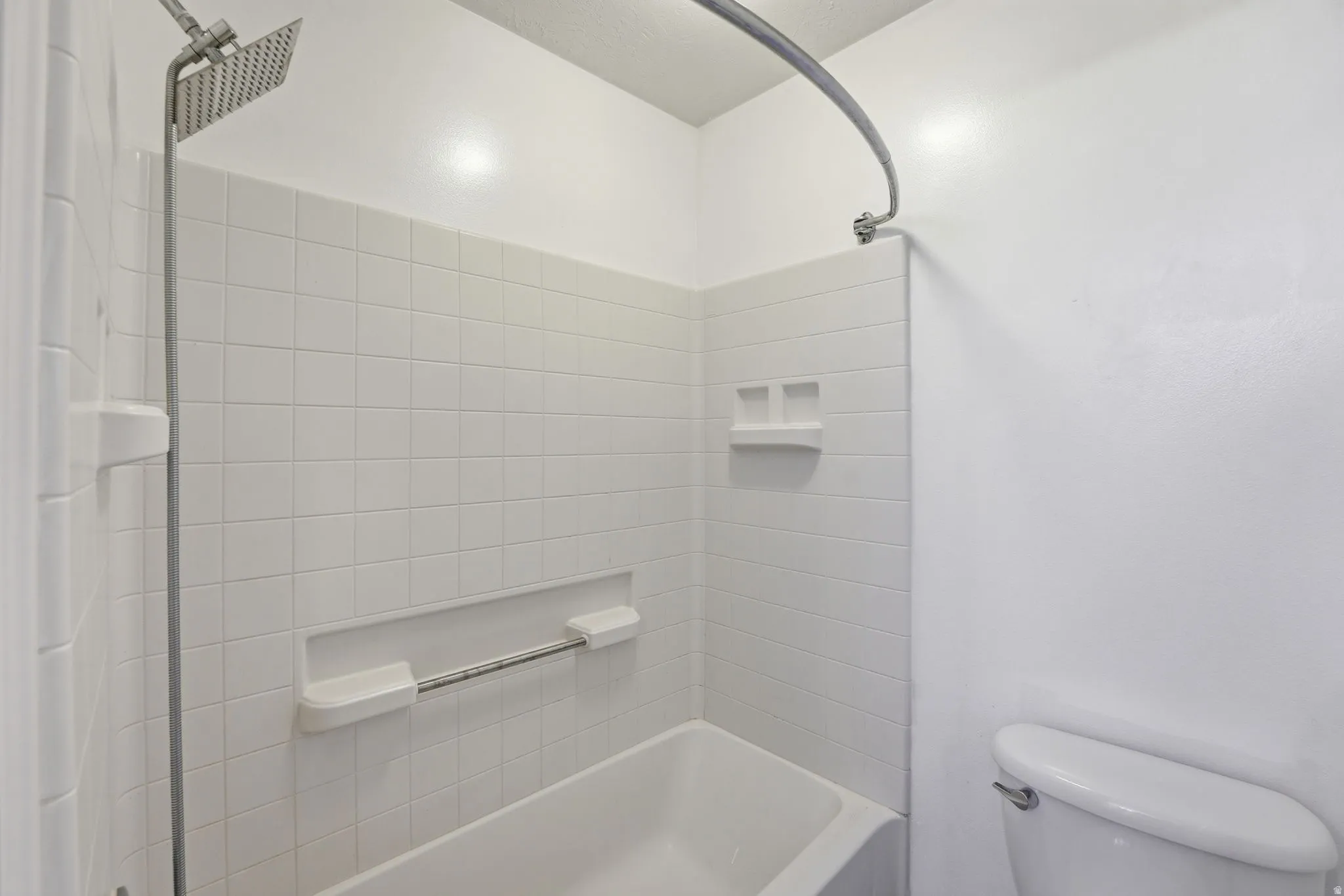 Master Bath-Shower/tub combination featuring white tile surround, recessed niche with integrated grab bar, and built-in soap dishes