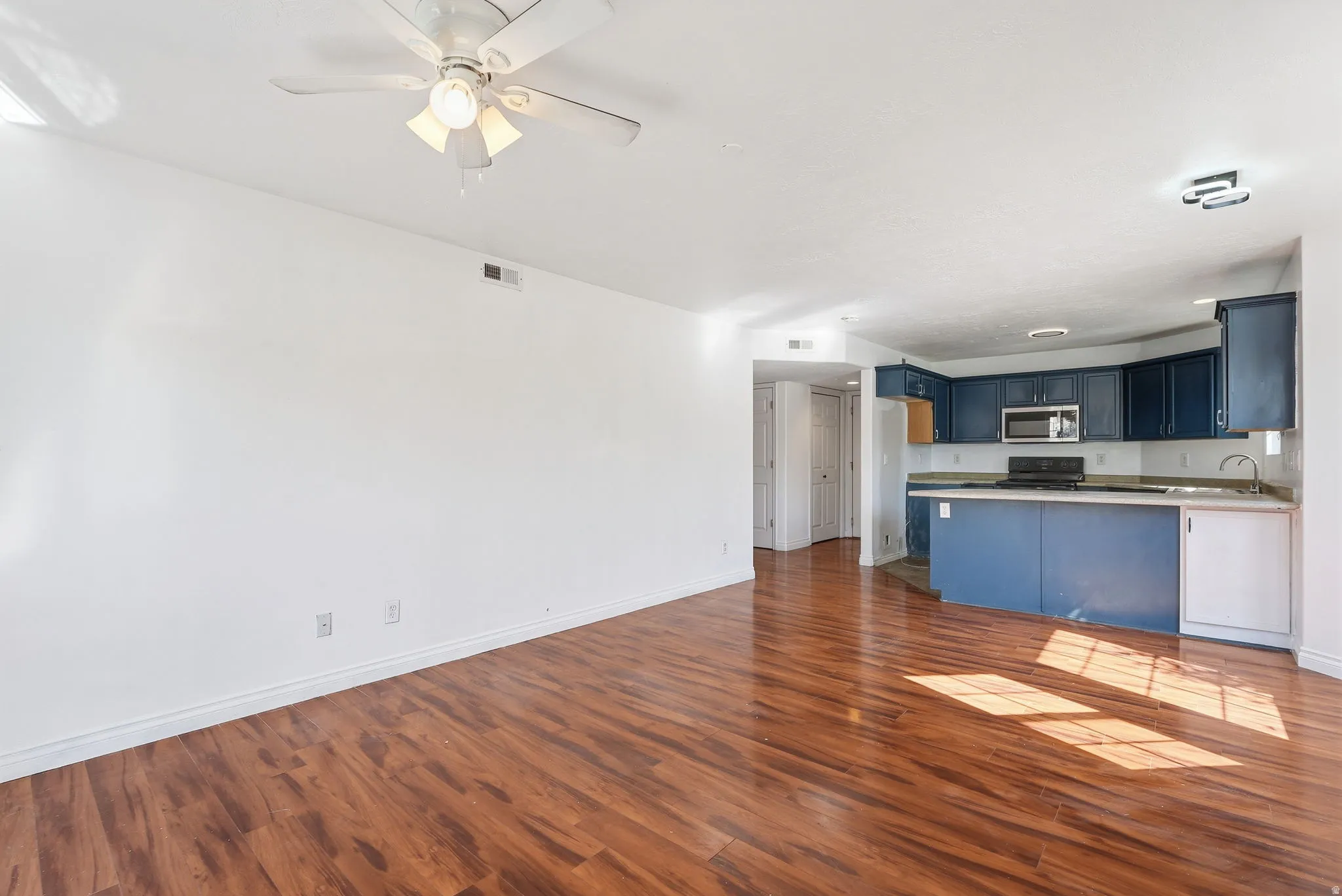 Open-concept living area featuring wood-finish flooring and a ceiling fan with integrated lighting