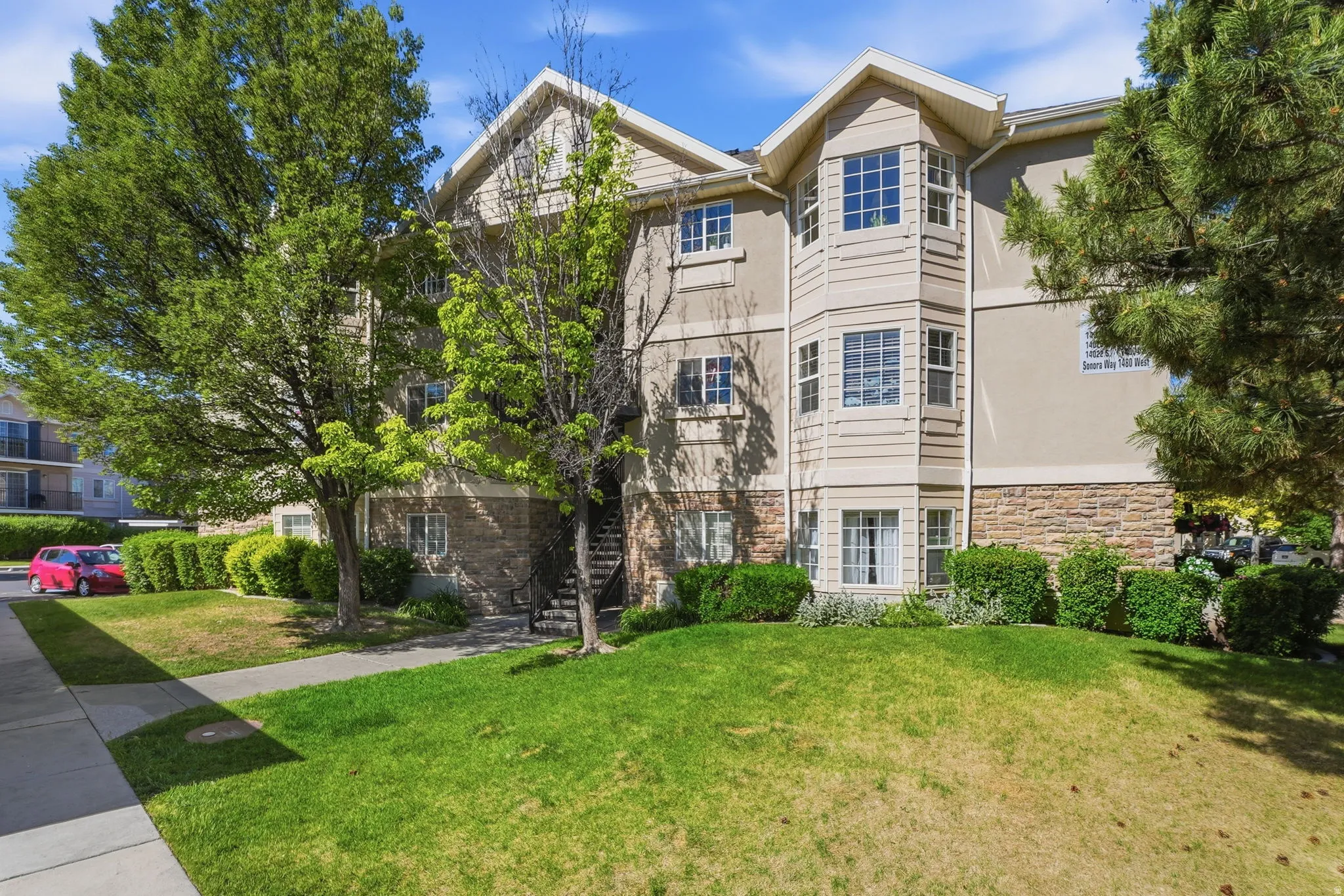 Multi-story building featuring a bay window design, stone veneer lower level, and stucco exterior