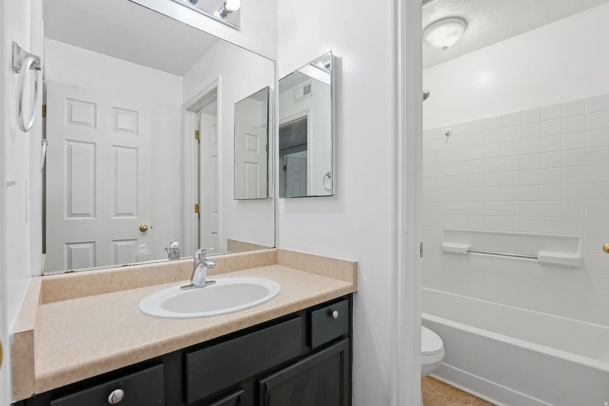 Main Bath with Tub/Shower and Toilet in seperate space. Featuring medicine cabinet for storage