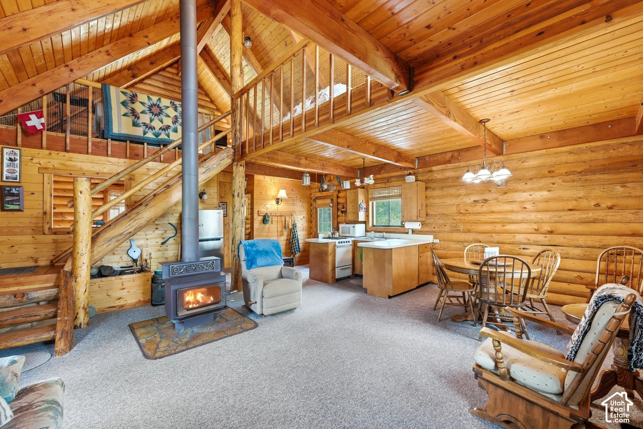 Expansive interior featuring exposed log walls, a wood-burning stove, and a vaulted wood-paneled ceiling