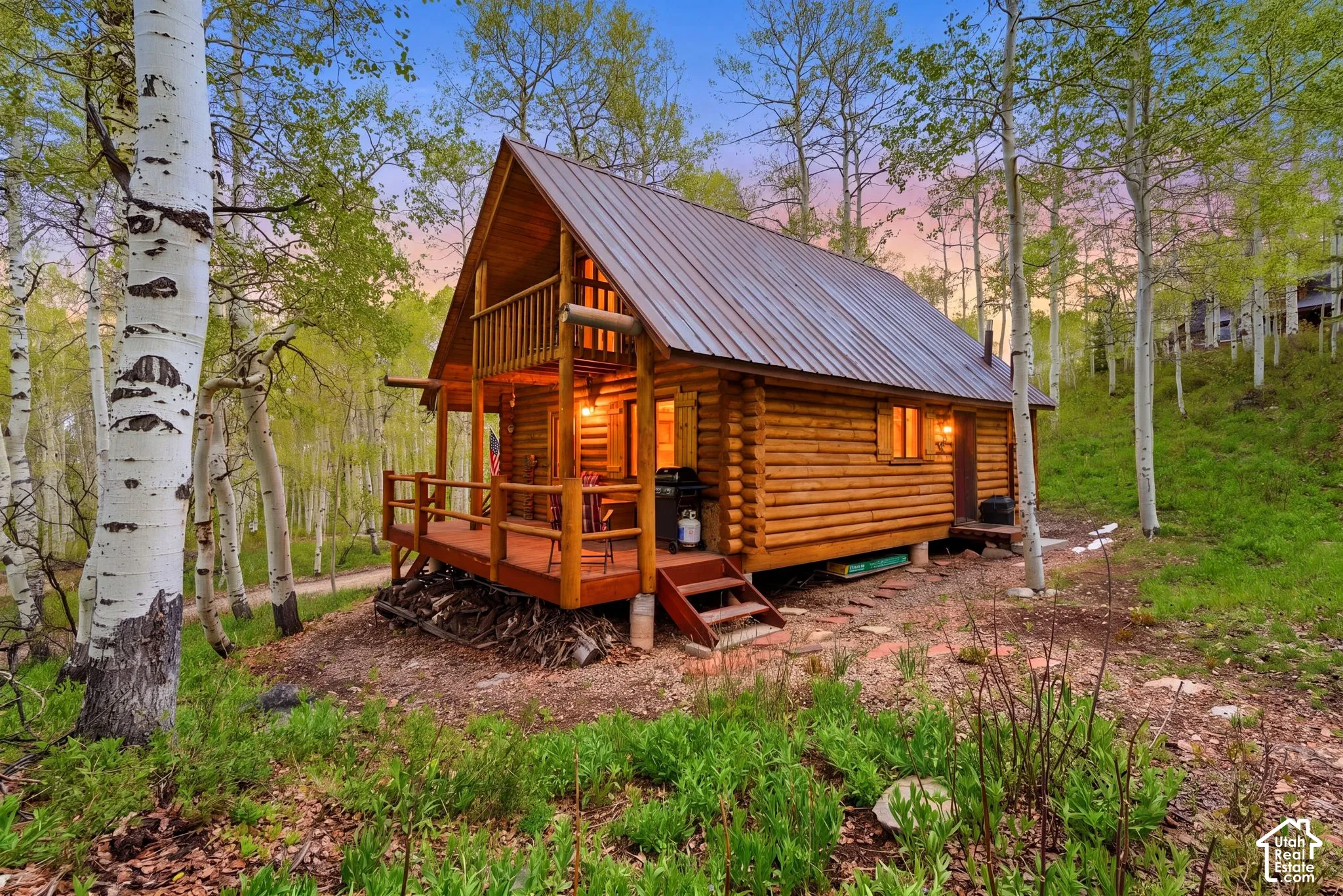 Log cabin exterior featuring a metal roof, a covered porch with wooden railings, and an upper-level balcony