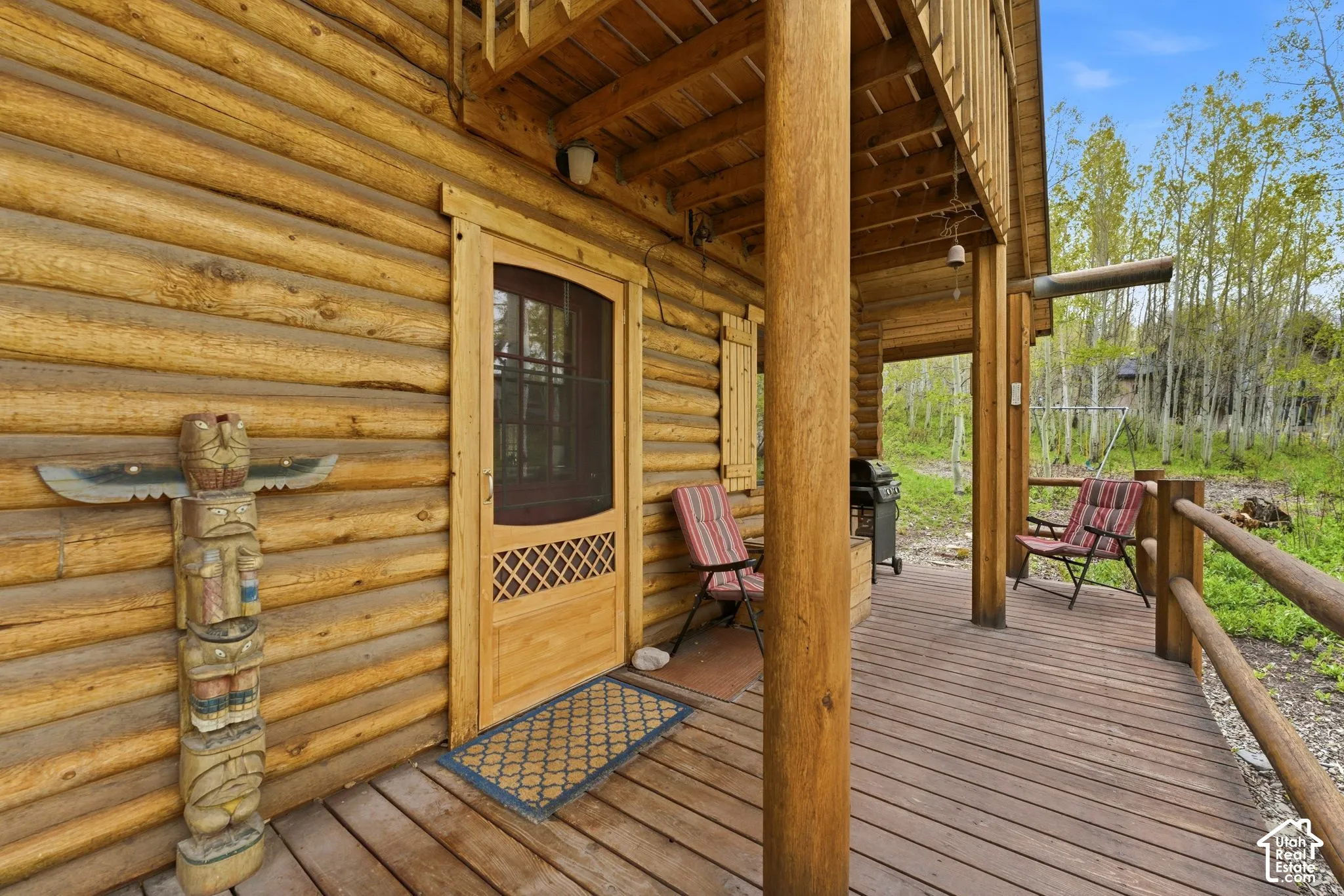 Rustic log cabin exterior featuring a covered wood deck