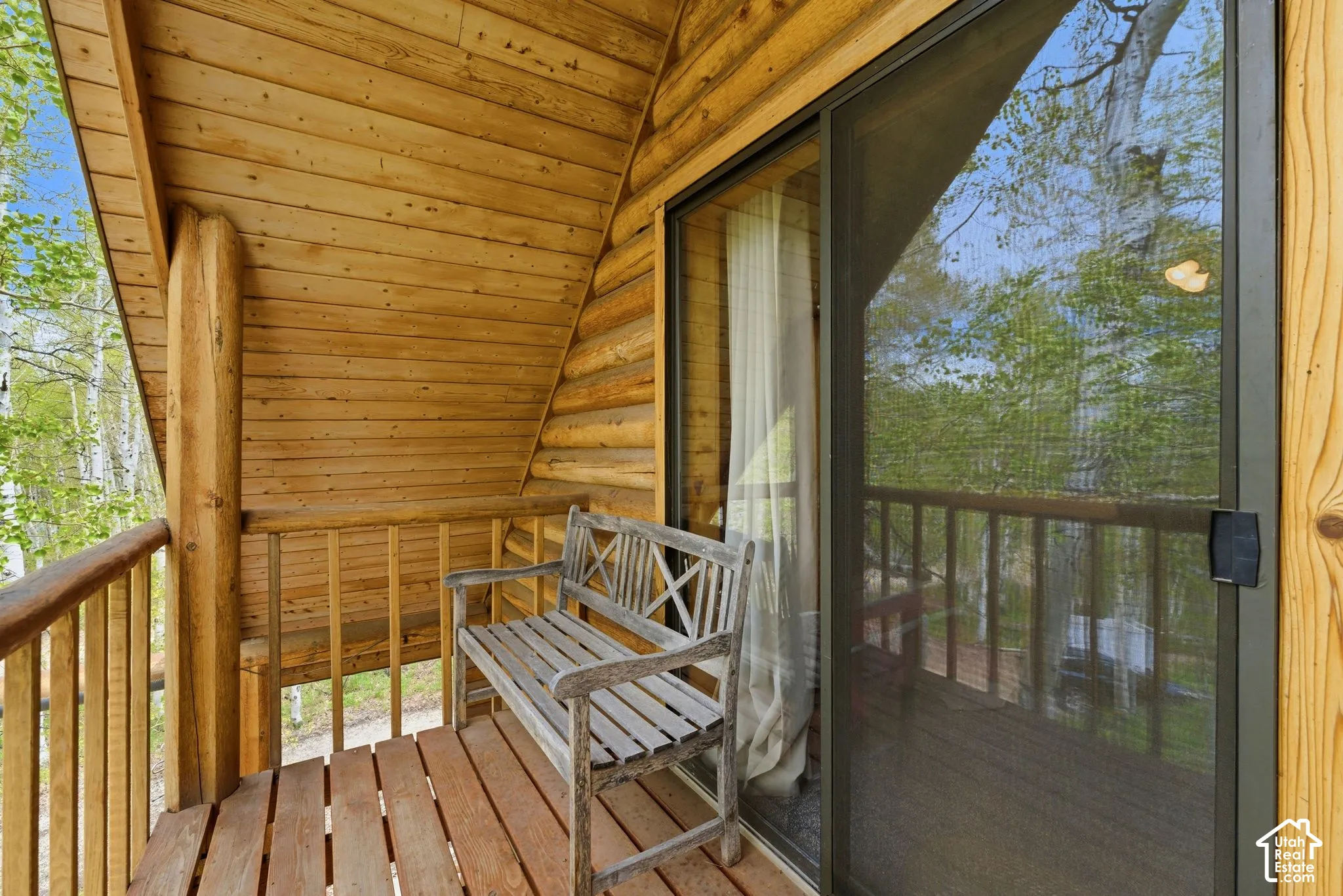 Wood-plank balcony with log structural elements, wood-plank flooring, and a sliding glass door
