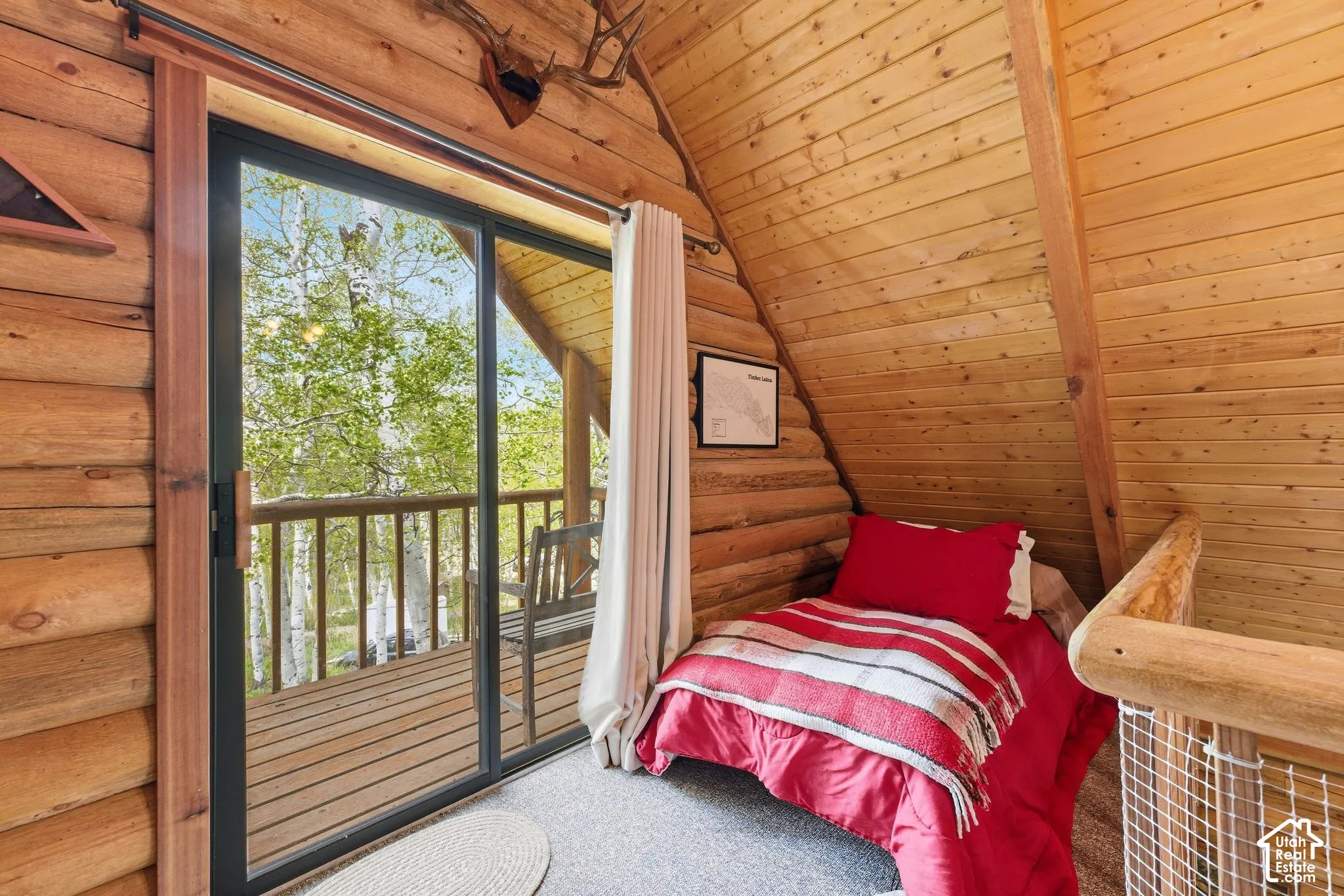 Sliding glass door opening to an outdoor deck with wood railings, surrounded by mature trees