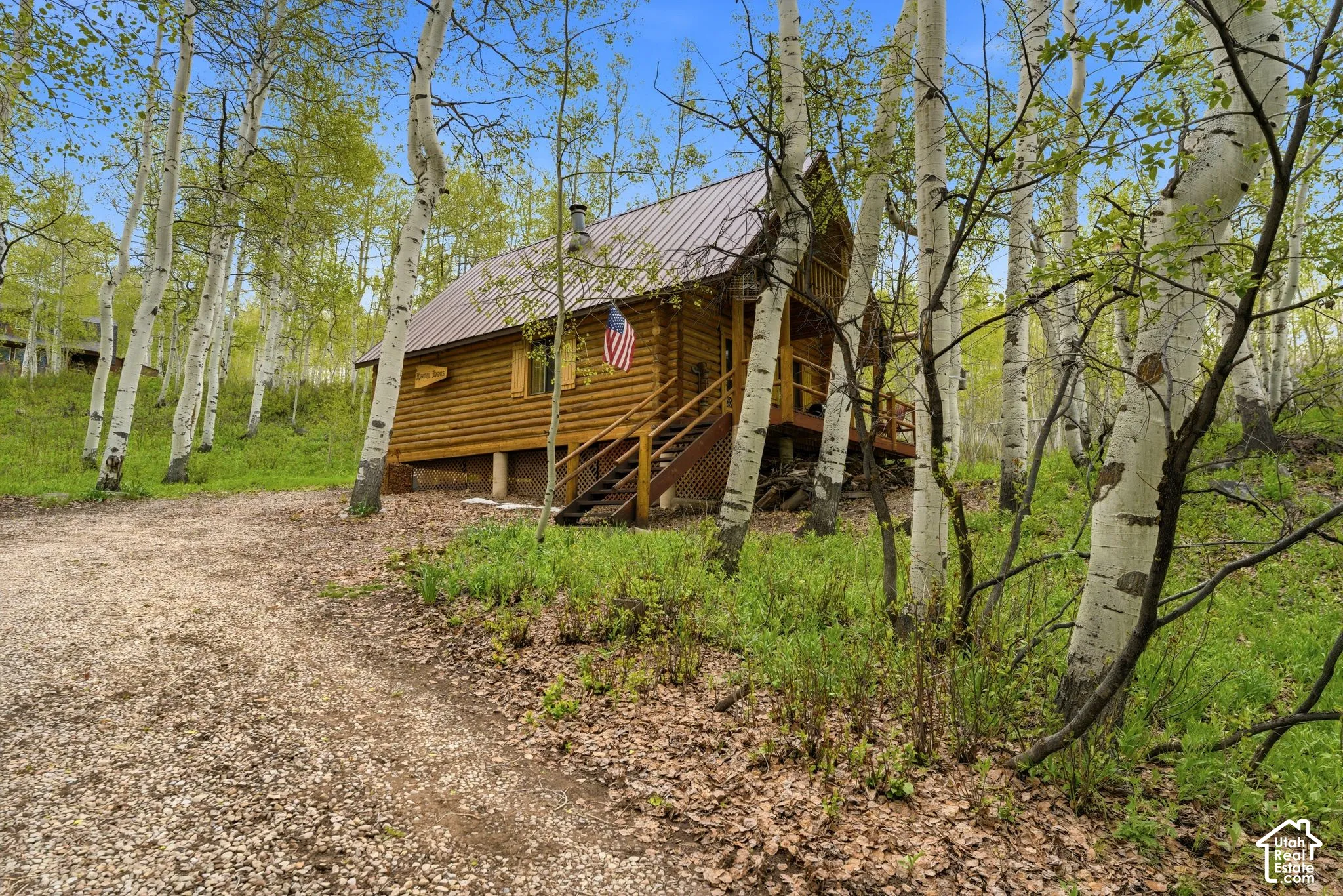 Log cabin exterior with a metal roof and a raised wooden deck
