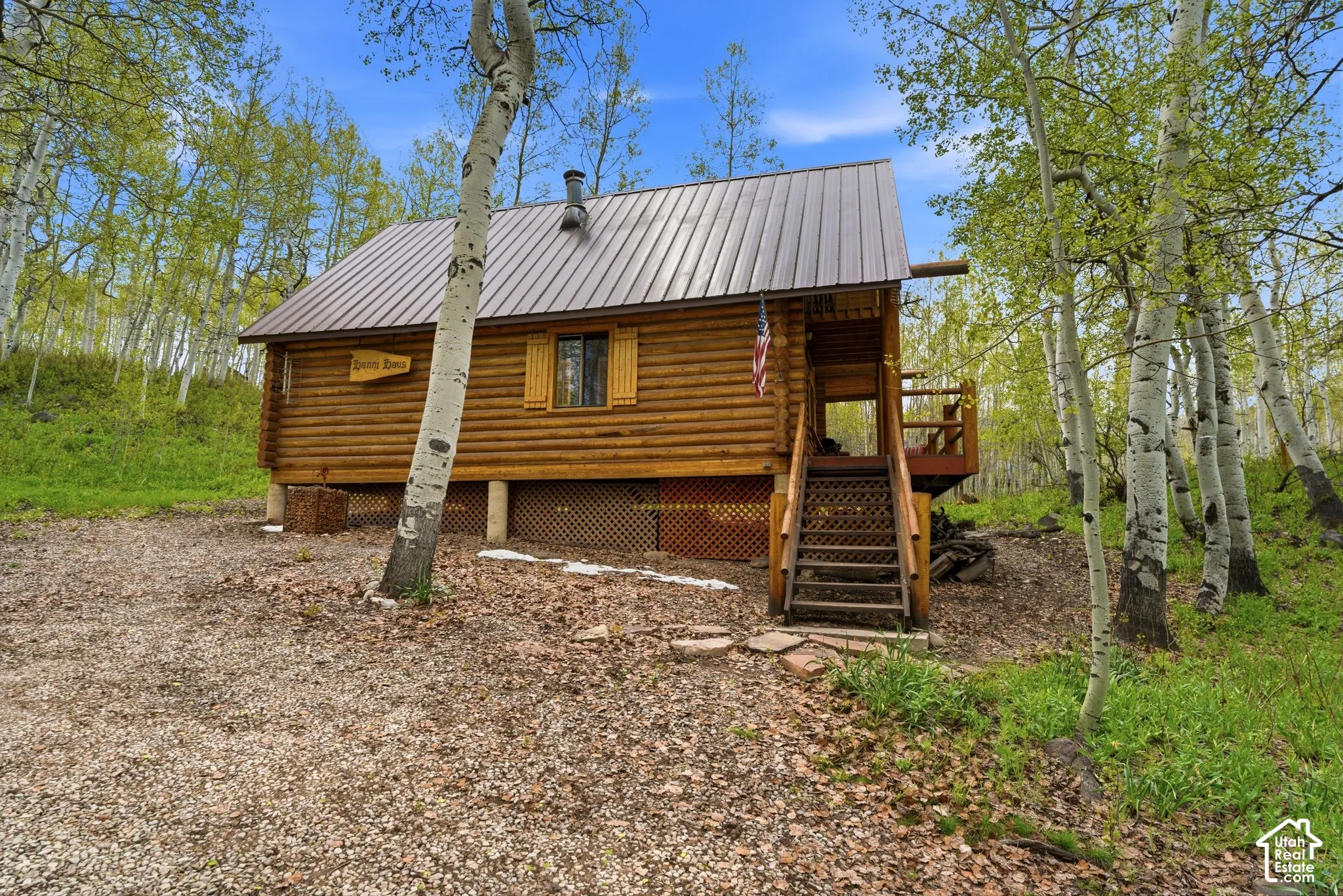 Log cabin exterior featuring a metal roof, wood siding, and an elevated porch with wood stairs