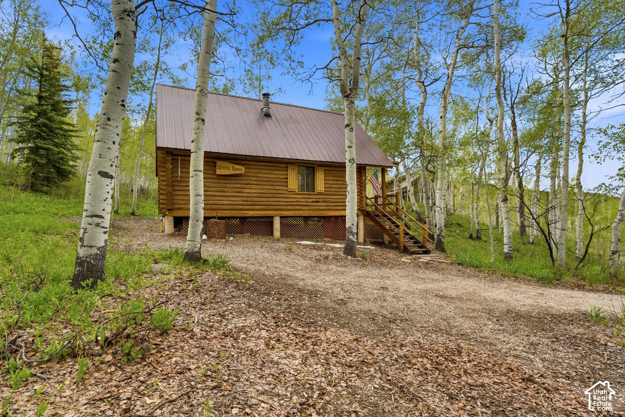 Log cabin exterior featuring a brown metal roof and a wood deck with stairs