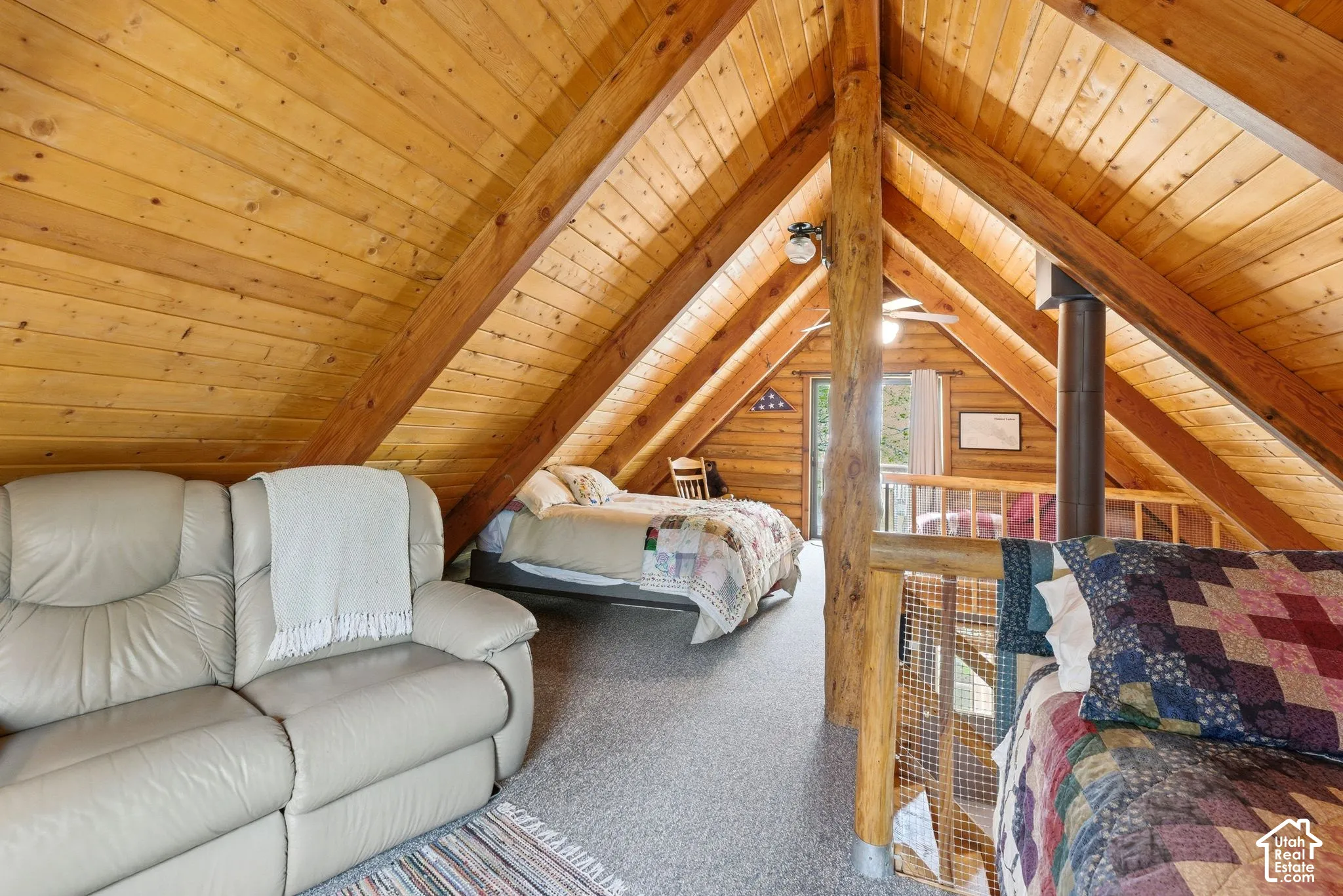 Vaulted wood-paneled ceiling with exposed wood beams, featuring a lofted layout with carpet flooring