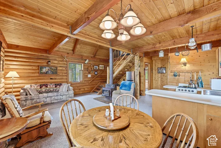 Open-concept living space featuring wood-paneled walls and ceiling with exposed beams