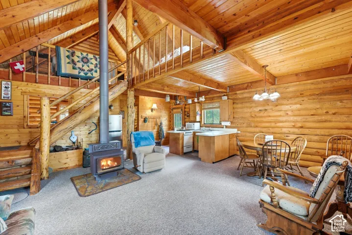 Expansive interior featuring exposed log walls, a wood-burning stove, and a vaulted wood-paneled ceiling