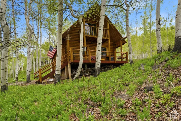 Log cabin residence featuring a gabled roof, natural wood siding, and a raised deck